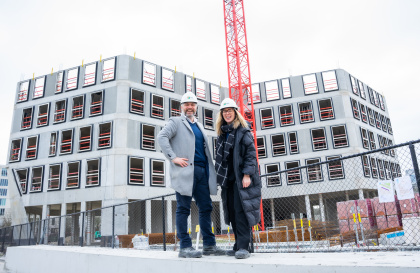 Two people in front of an Upoffiz building under construction.